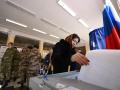 Una mujer vota en un colegio electoral en Rusia bajo una fuerte presencia militar