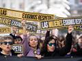 Varias personas sujetan carteles durante una manifestación por el 25N