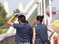 Un hombre cruza el puente de la Barqueta usando una carpeta para protegerse de las altas temperaturas, a 24 de agosto en Sevilla (Andalucía, España). La ola de calor acaba este jueves con la llegada de una vaguada que bajará las temperaturas.