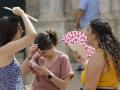 Tres personas se protegen del calor con abanicos en Valencia