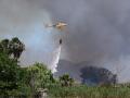 Un helicóptero echa agua a una zona afectada por un incendio