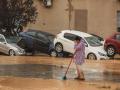 Una mujer realiza labores de limpieza junto a vehículos destrozados tras el paso de la DANA por el barrio de La Torre de Valencia