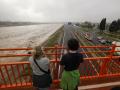 Dos personas contemplan el nuevo cauce del Turia repleto de agua a causa de la gota fría