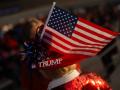 Un partidario lleva un sombrero con una bandera estadounidense y un pin con la palabra "Trump"