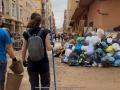 Dos chicas voluntarias pasan al lado de una montaña de basura