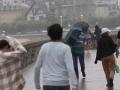 Varias personas caminan bajo la lluvia en la playa de Ondarreta, en San Sebastián