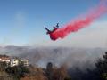 Un avión de extinción de incendios arroja el retardante de fuego Phos-Chek cerca de las casas durante el incendio de Palisades