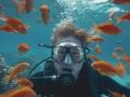 Imagen de un buceador junto a a decenas de peces