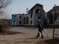 Una mujer con bolsas camina cerca de un edificio dañado en Kostyantynivka, región de Donetsk
