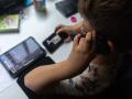 Un niño usa el teléfono móvil y una tablet