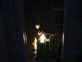 Un niño con una lámpara mira desde el balcón la calle todavía a oscuras esta madrugada en el centro de Barcelona durante el corte de suministro eléctrico