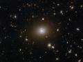 Esta imagen del telescopio espacial Hubble de la NASA/ESA muestra la galaxia remota HerS 020941.1+001557, que aparece como un arco rojo que rodea parcialmente una galaxia elíptica en primer plano