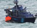 Una lancha de aduanas recoge un barco hundido y un trozo de barco arrastrado a las rocas junto al faro,en la ría de Muros