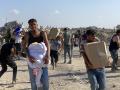 Palestinos observan a su alrededor en alerta tras los disparos mientras palestinos desplazados reciben paquetes de alimentos de una fundación respaldada por Estados Unidos que se compromete a distribuir ayuda humanitaria en el oeste de Rafah, en el sur de la Franja de Gaza