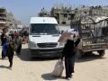 Una mujer camina con un saco en la cabeza y arrastra otro por una carretera utilizada por desplazados que huyen de Khan Yunis hacia el oeste, en dirección a Al-Mawasi, en el sur de la Franja de Gaza