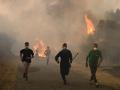 Personas corren por una zona quemada durante un incendio forestal cerca del pueblo de Larouco, en la provincia de Ourense.