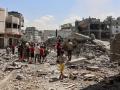 Un grupo de palestinos se reúne cerca de los escombros de un edificio de la Ciudad de Gaza