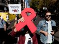 Manifestantes portan un lazo rojo y pancarta con lema 'Por los derechos de las personas con VIH'