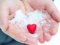 Hands giving a red heart in the snow, Valentine's Day, the theme of donation