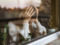 Young woman in depression. Portrait of her through a window.