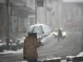Man with umbrella during snow storm in the street
