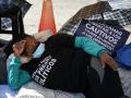 A relative of a political prisoner sits on the ground in front of police officers during a protest outside the Bolivarian National Police (PNB) Zona 7 prison in Caracas on February 14, 2026. About a dozen relatives of political prisoners began a hunger strike outside a prison facility in Caracas on February 14, AFP observed, after Parliament postponed the approval of a historic amnesty bill two days earlier. (Photo by Federico PARRA / AFP)