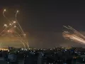 La Cúpula de Hierro israelí (izquierda), desplegada para detener un ataque de misiles lanzado por Hamas desde Gaza (derecha), en 2021