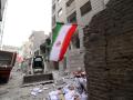 Una bandera iraní ondea mientras una excavadora llega para ayudar a retirar los escombros de los edificios destruidos tras el ataque militar a la capital iraní, Teherán