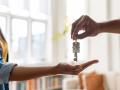 Close-up on a real estate agent giving the keys of her new house to a woman – home ownership concepts