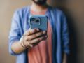 An anonymous handsome Indian male using his new smartphone to take a selfie.