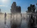 Varios niños se refrescan en una fuente durante la tercera ola de calor en Madrid