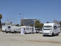 Foto de contraste con pisos de lujo al fondo y autocaravanas en un asentamiento