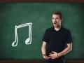 Young attractive music teacher singing in front of chalkboard with a note