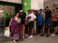 Una joven sale del supermercado mientras varios jóvenes la miran.