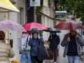 Varias personas se protegen de la lluvia por el centro de Valènci