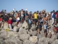 Miembros de la Cruz Roja reparten comida a los inmigrantes en una playa, a 21 de agosto de 2026