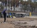 Vecinos de Barcelona pasean bajo la lluvia en la playa de la Barceloneta