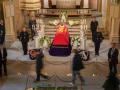 Los dolientes desfilan silenciosamente frente al féretro del rey después de que se abriera la fila para el velatorio el martes por la tarde.