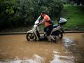 Una mujer empujando su moto en un barrio de Barcelona debido a las inundaciones