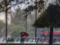 Imagen de una mujer protegiéndose de la lluvia en Valencia