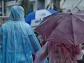 Dos personas con paraguas y chubasqueros pasen por la calle en un día de lluvias y tormentas