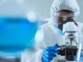 Imagen de archivo de un científico mirando un microscopio vestido con un EPI