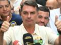 Brazil's right-wing senator and presidential candidate for the Liberal Party (PL) Flavio Bolsonaro gives thumbs up in front of Rio de Janeiro gubernatorial candidate Douglas Ruas (C, back), as he leaves a polling station after voting during the presidential election in Rio de Janeiro, Brazil, on October 4, 2026. Brazilians head to the polls deeply polarized in a nail-biting first-round presidential election and under the shadow of US President Donald Trump, who has backed conservative candidates in recent elections in Latin America. (Photo by MAURO PIMENTEL / AFP)