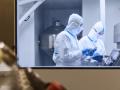 Científicos con trajes limpios usando tabletas digitales en experimentos en laboratorio
