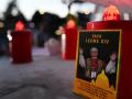 Una fotografía del papa León XIV y unas velas colocadas junto a la estatua de Juan Pablo II frente al Hospital Universitario Gemelli
