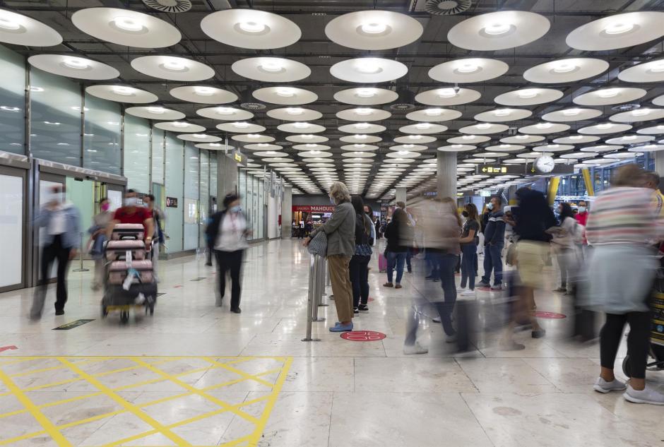 Un hombre espera mientras otros pasajeros llegan a la Terminal T4 del Aeropuerto Adolfo Suárez Madrid - Barajas