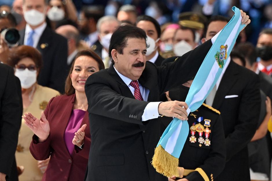 El expresidente Manuel Zelaya y marido de Xiomara Castro (detrás) sostiene la banda presidencial que luego fue impuesta a la nueva presidenta de Honduras