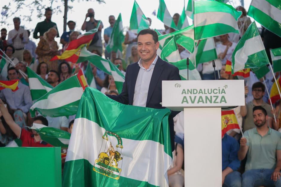Juanma Moreno con una bandera de Andalucía en un mitin en Málaga