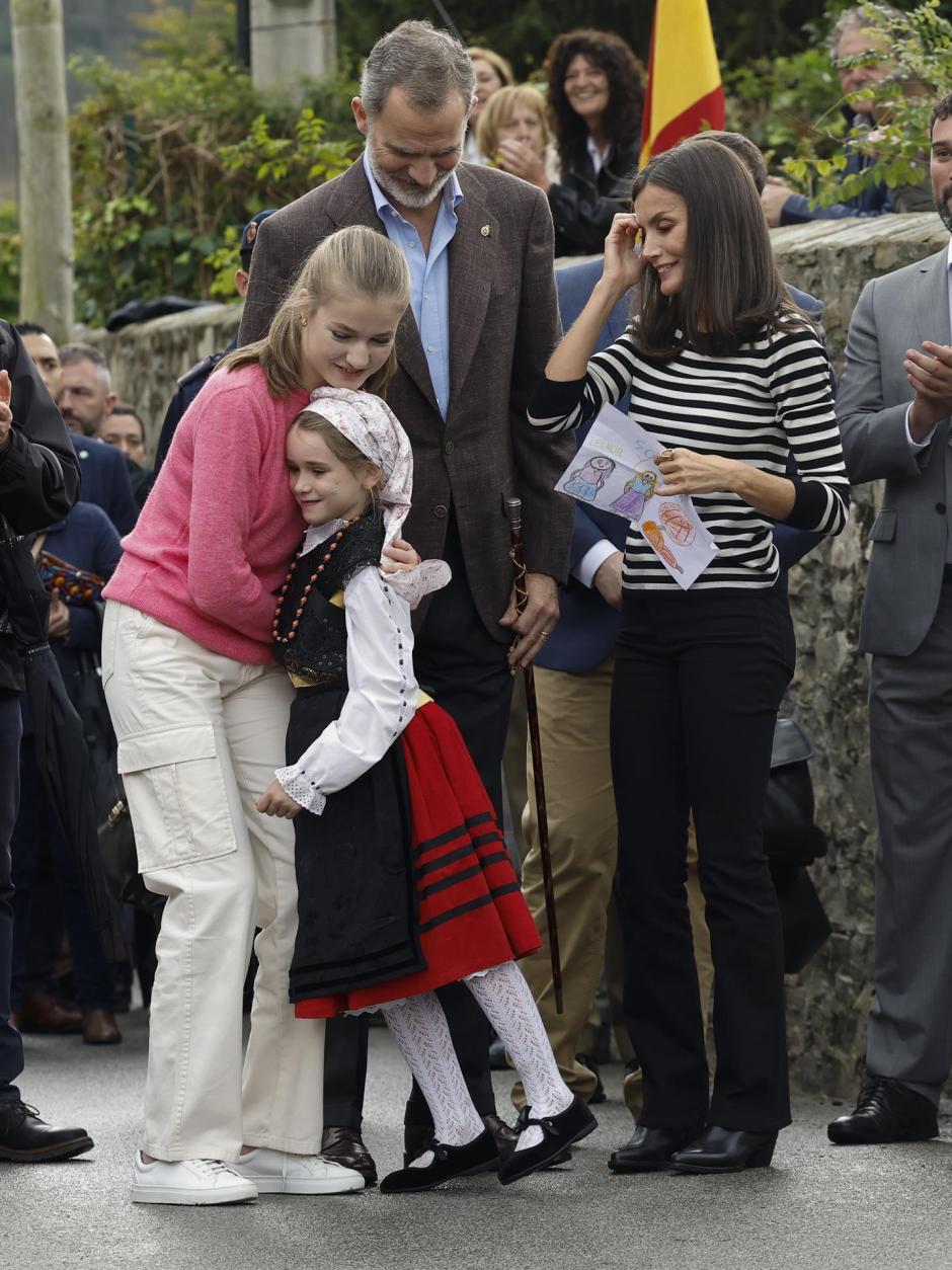 La Princesa de Asturias Leonor (i) abraza a una pequeña en presencia de los Reyes Felipe VI y Letizia durante su visita a la parroquia de Cadavedo