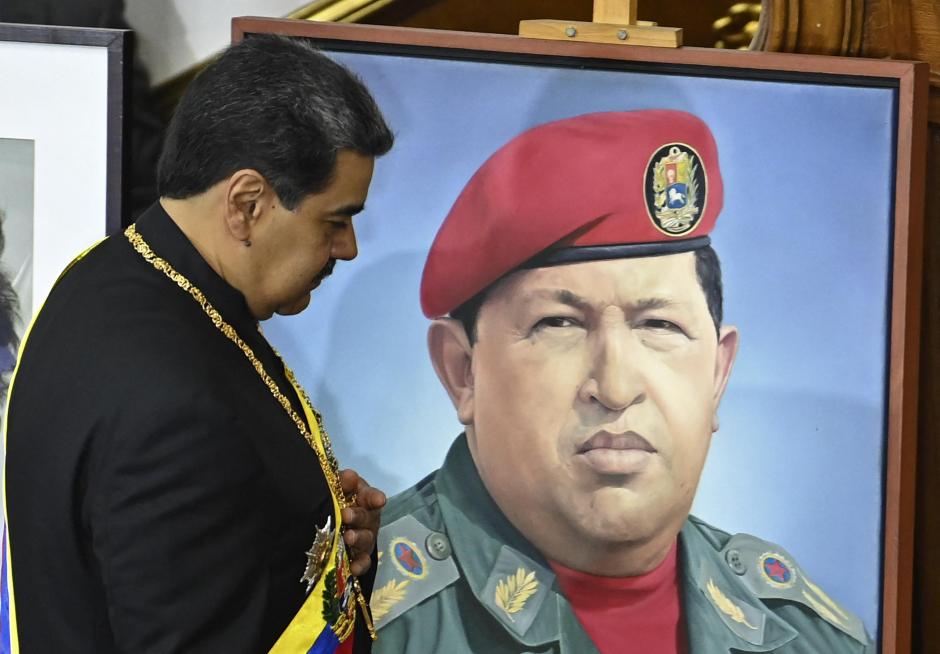 Nicolás Maduro, pasa junto a un retrato del difunto presidente Hugo Chávez mientras presenta su informe anual a la Asamblea Nacional en Caracas